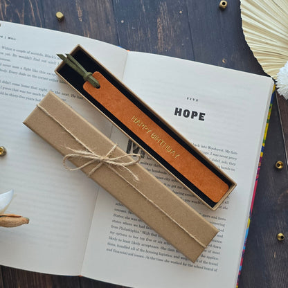 A leather bookmark with a green handle and gold lettering reading 'I AM NOT ALONE'