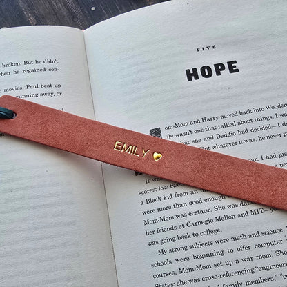 A pink leather bookmark with gold lettering