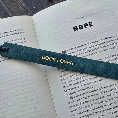 A dark teal leather bookmark with gold lettering that reads 'BOOK LOVER'