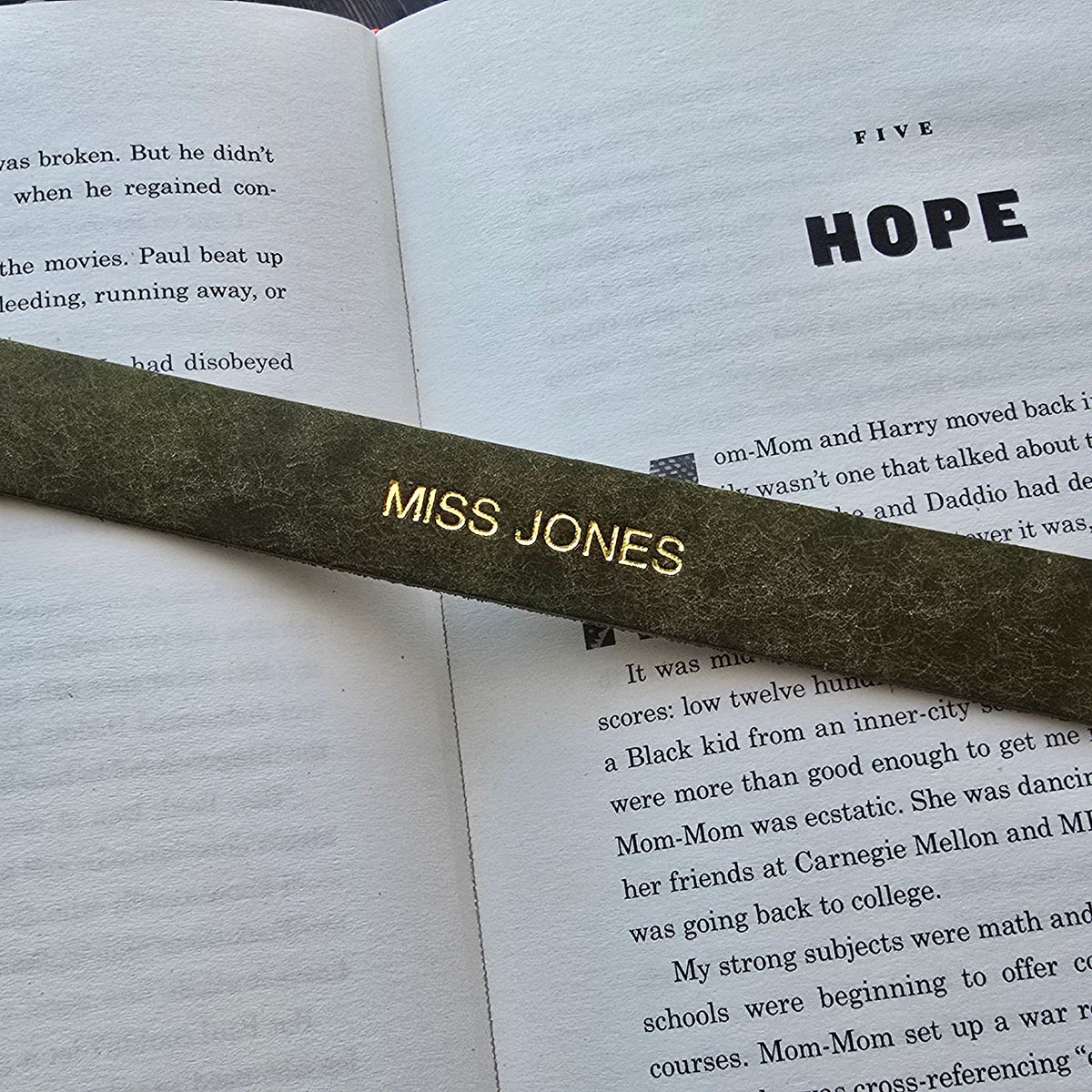 A dark olive green wooden bookmark with gold foil lettering reading 'MISS JONES'