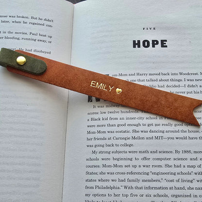 A personalized brown leather bookmark with gold lettering and a brass grommet