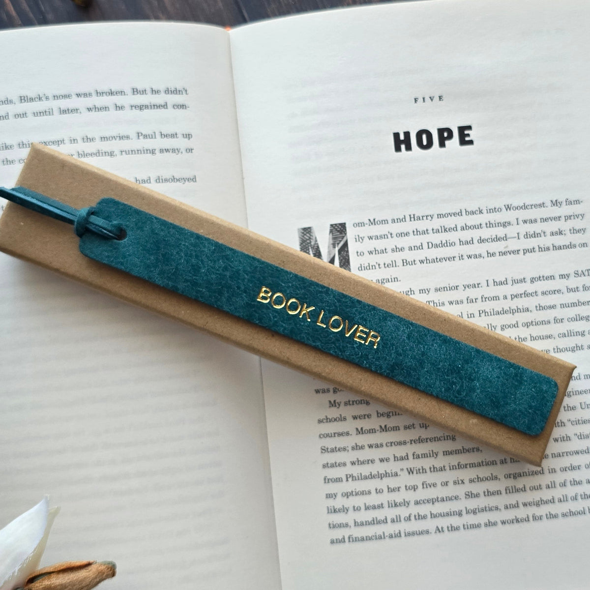A teal blue velvet bookmark with gold foil lettering that reads 'BOOK LOVER'